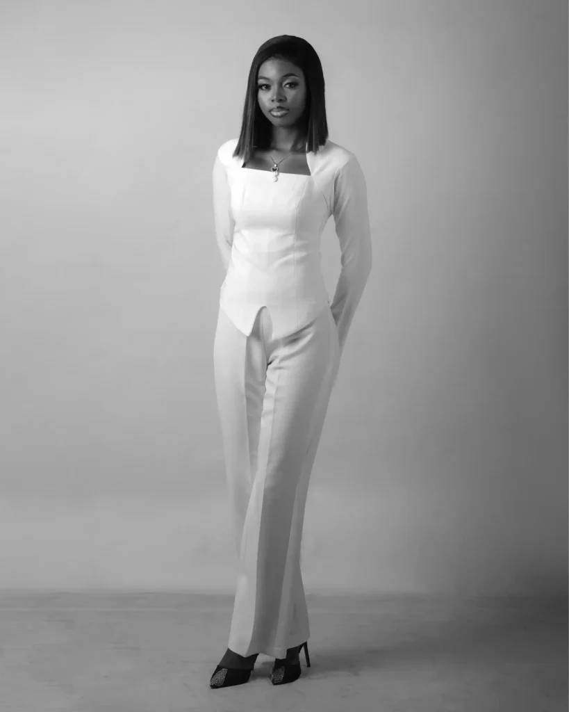 A woman in a monochromatic oatmeal-colored cashmere set standing in a modern architectural setting.